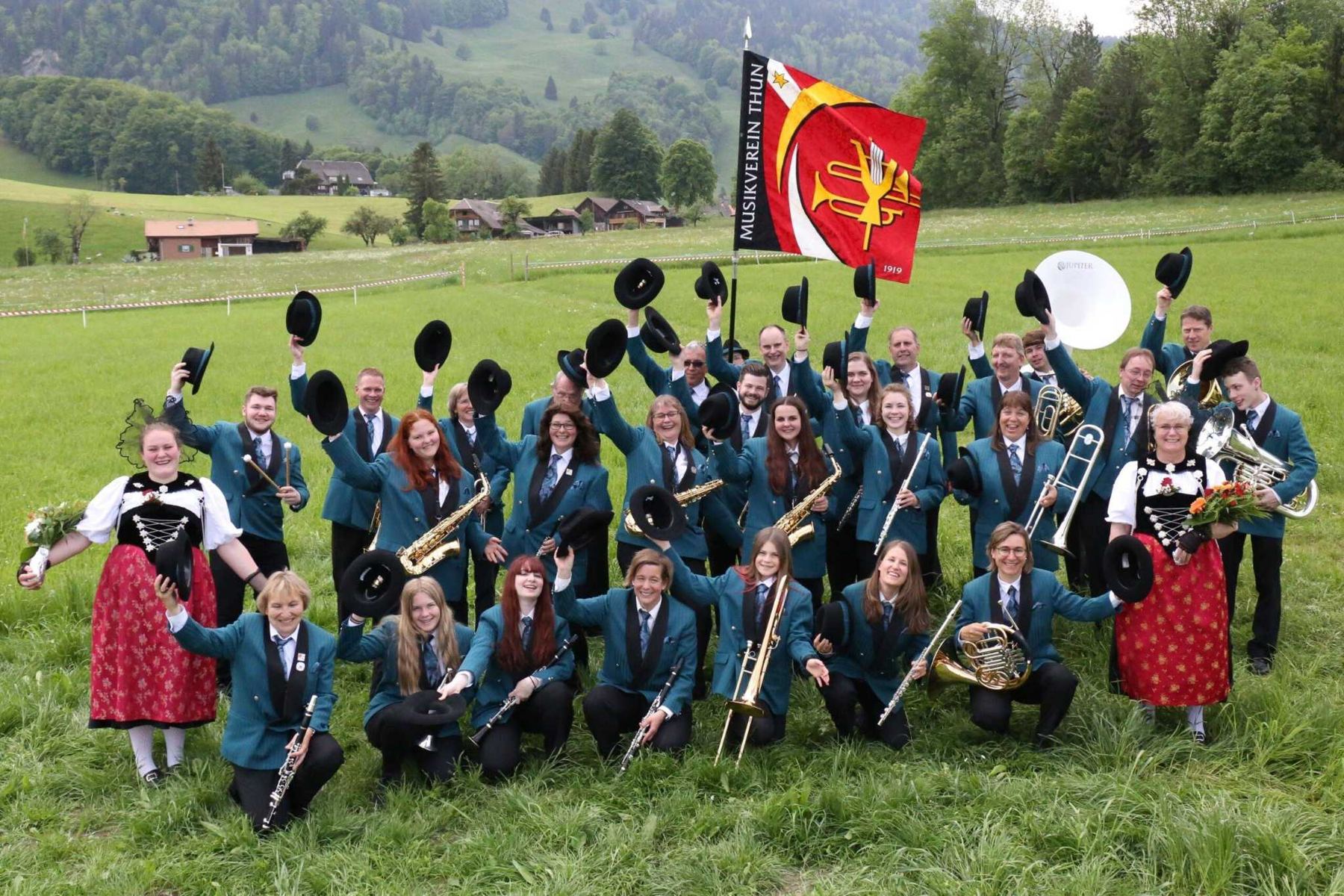 Der Musikverein Thun jubelt mit Fahne auf der Wiese